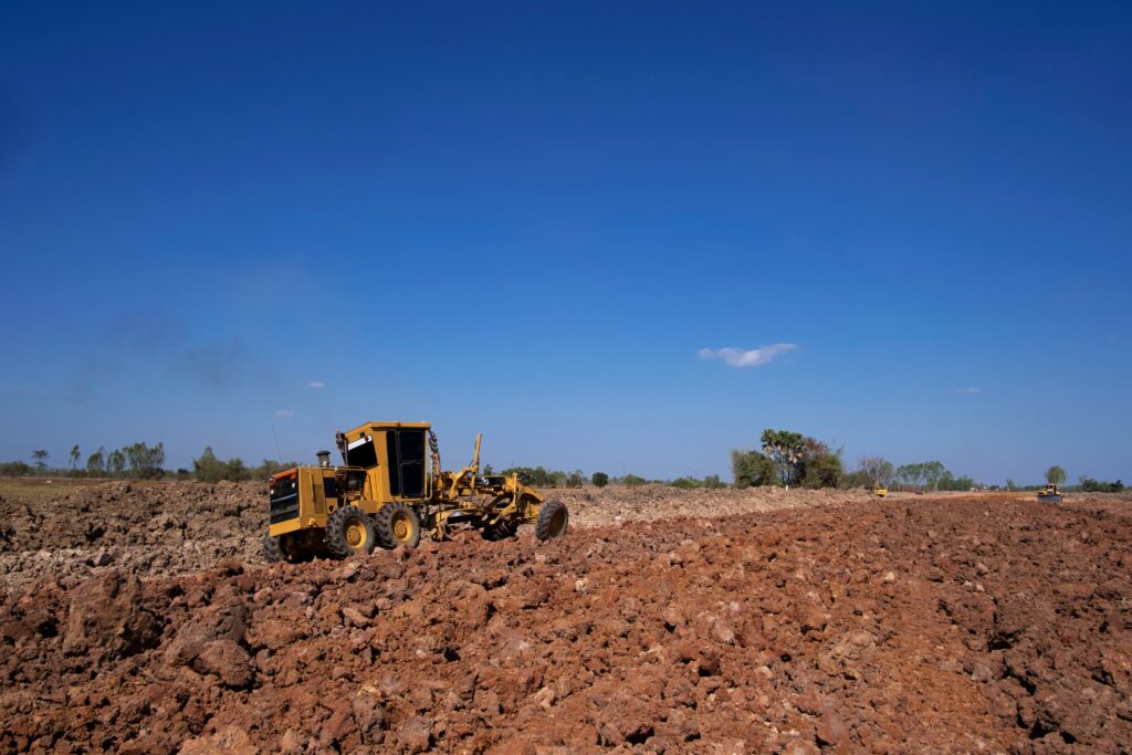 motor grader pushing dirt on a field